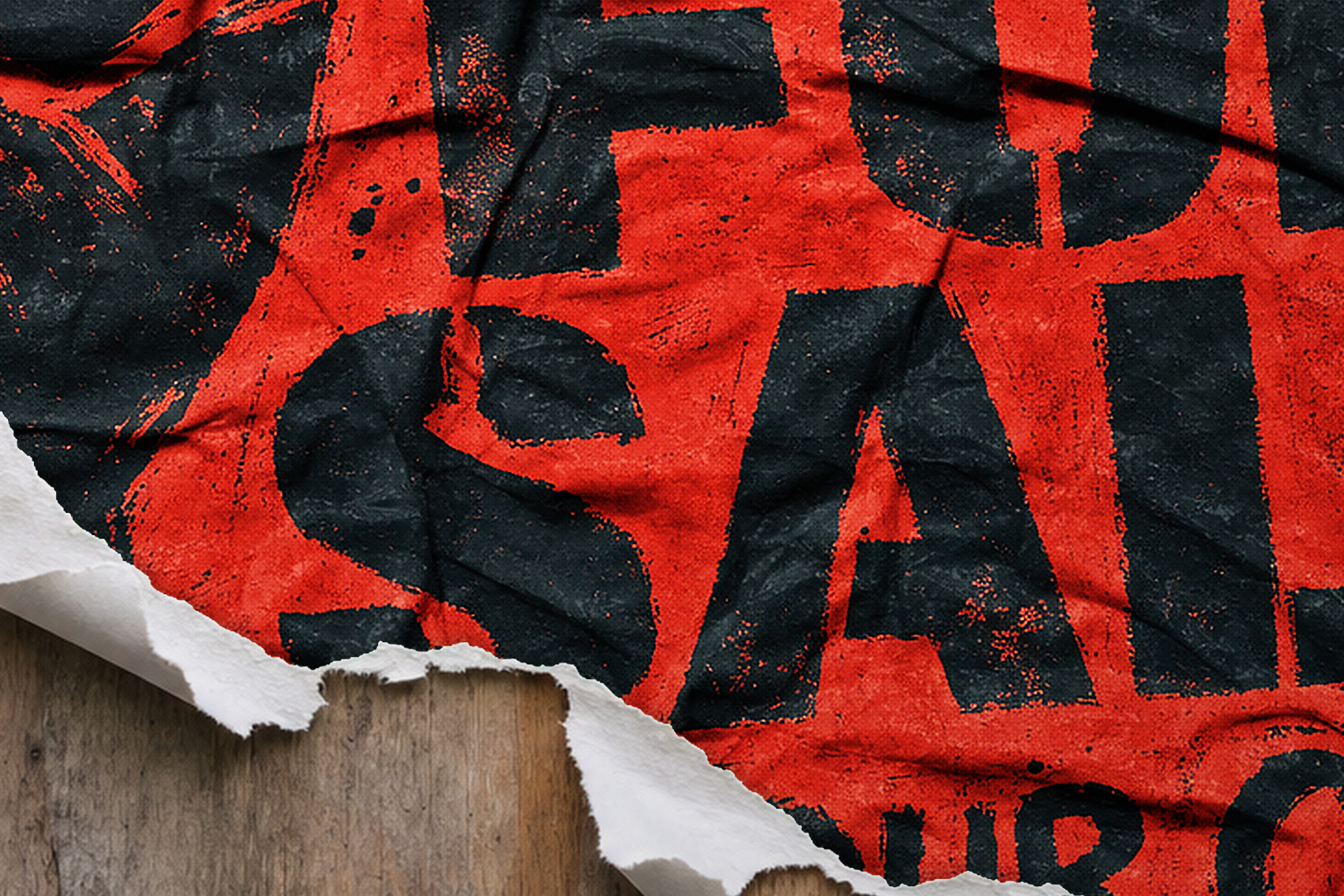 Grunge poster with oversized cropped black lettering on crumpled red paper, torn to reveal wood beneath